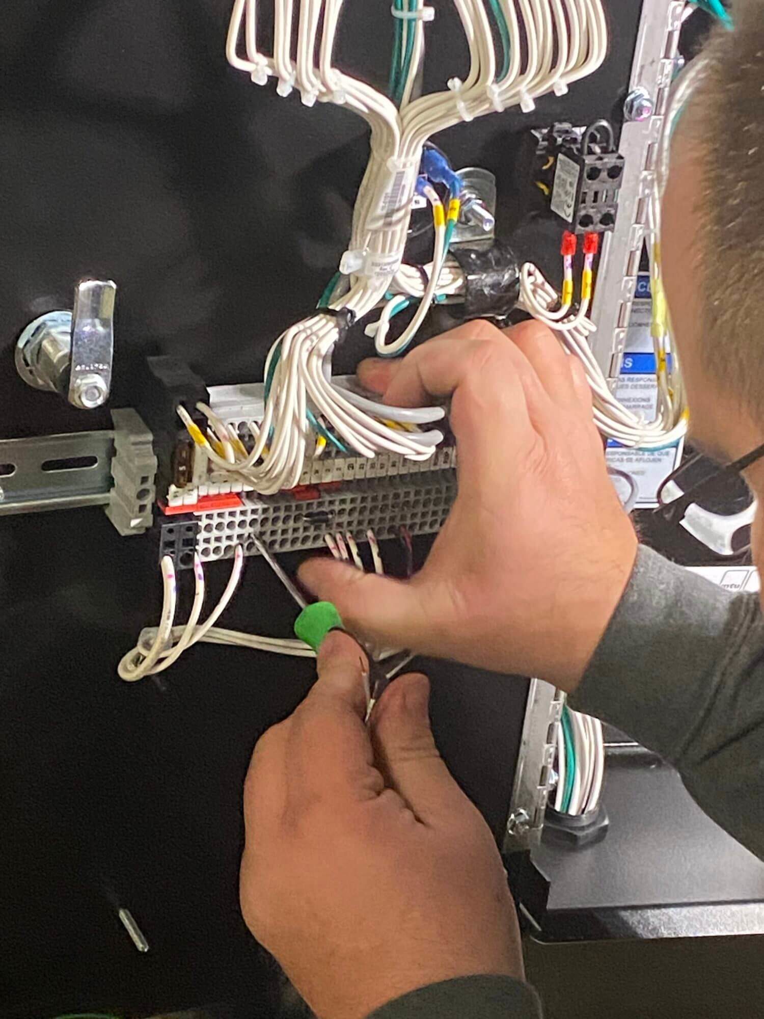 close up of tech working on circuit board with green screwdriver