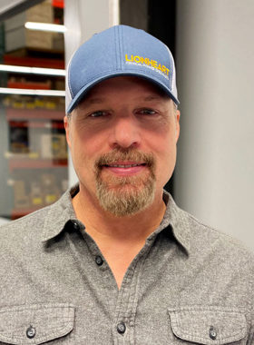 smiling employee looking at the camera in a lionheart baseball hat