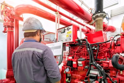 man in a grey hard hat looking at a large red commercial generator