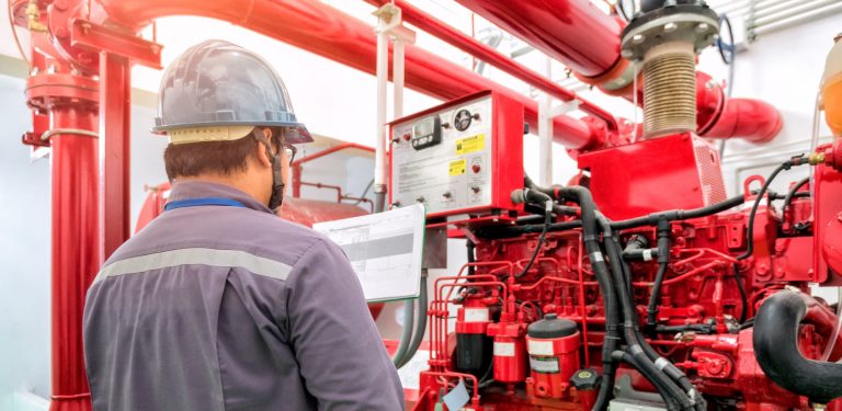 man in a grey hard hat looking at a large red commercial generator