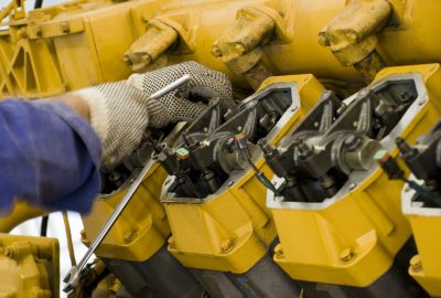 closeup of a gloved hand working on a yellow commercial generator