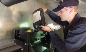 man in a blue hat pours liquid into machine