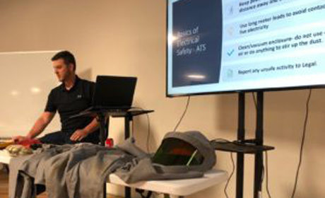 man giving a presentation behind a table with a grey protective suit