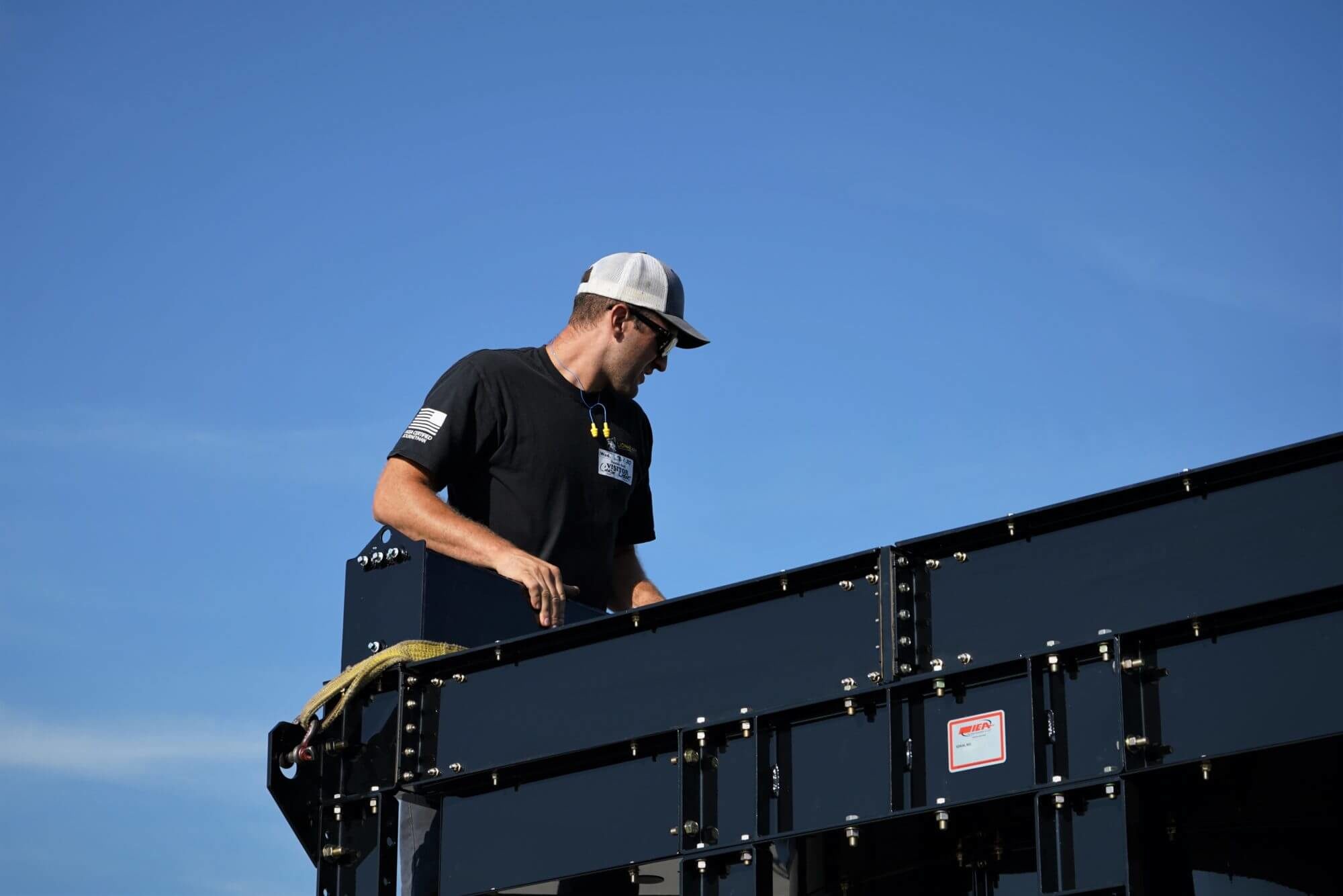 tech in white baseball hat framed against the sky